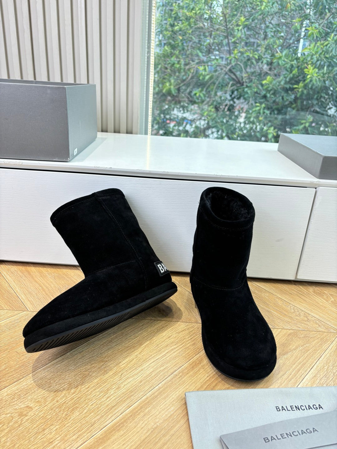 Black suede ankle boots, low stacked heel, side logo, pair on wooden floor