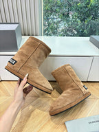 Tan suede ankle boots, pair on floor, pull-tab branding detail