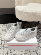 White low-top sneakers pair view, lace-up front and logo on tongue