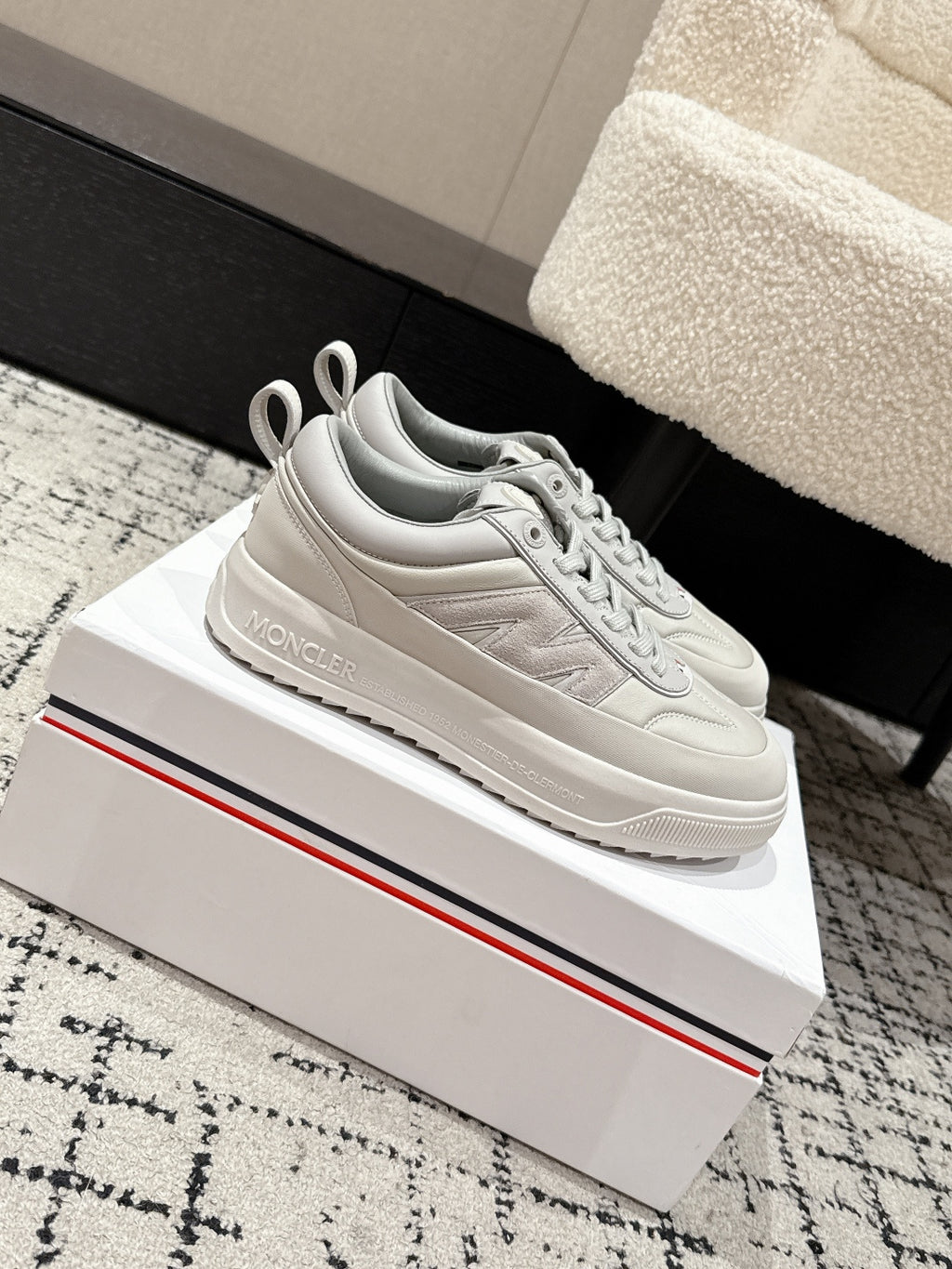White low-top sneakers, side profile with lace-up and logo patch