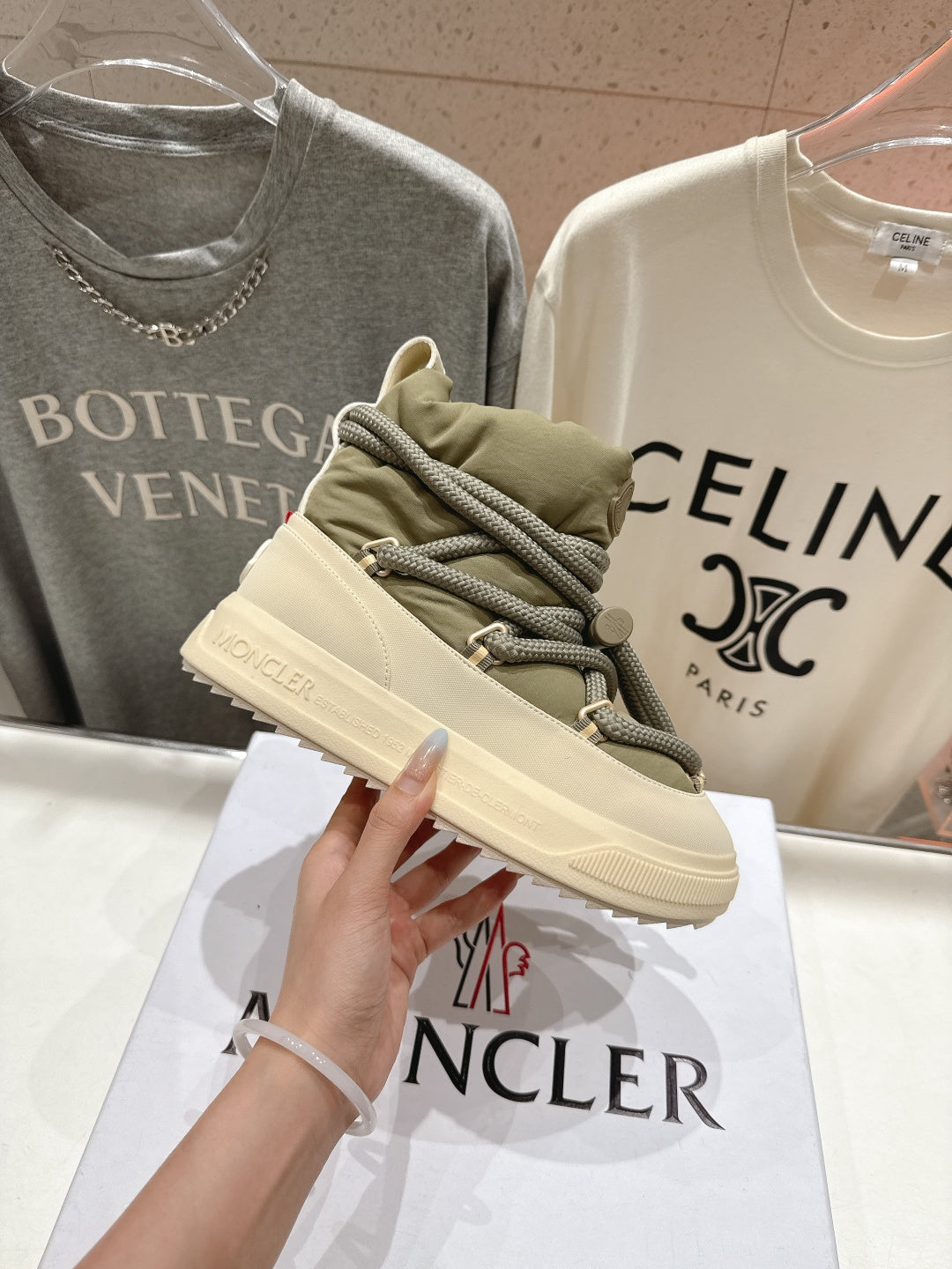 Moncler sneaker front view, beige upper with olive laces and padded tongue