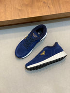 Prada unisex suede sneakers in dark blue, angled top view with gold triangle logo