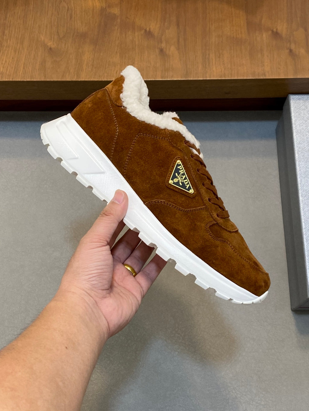 Brown suede lace-up sneaker with shearling collar and white tread sole, logo patch
