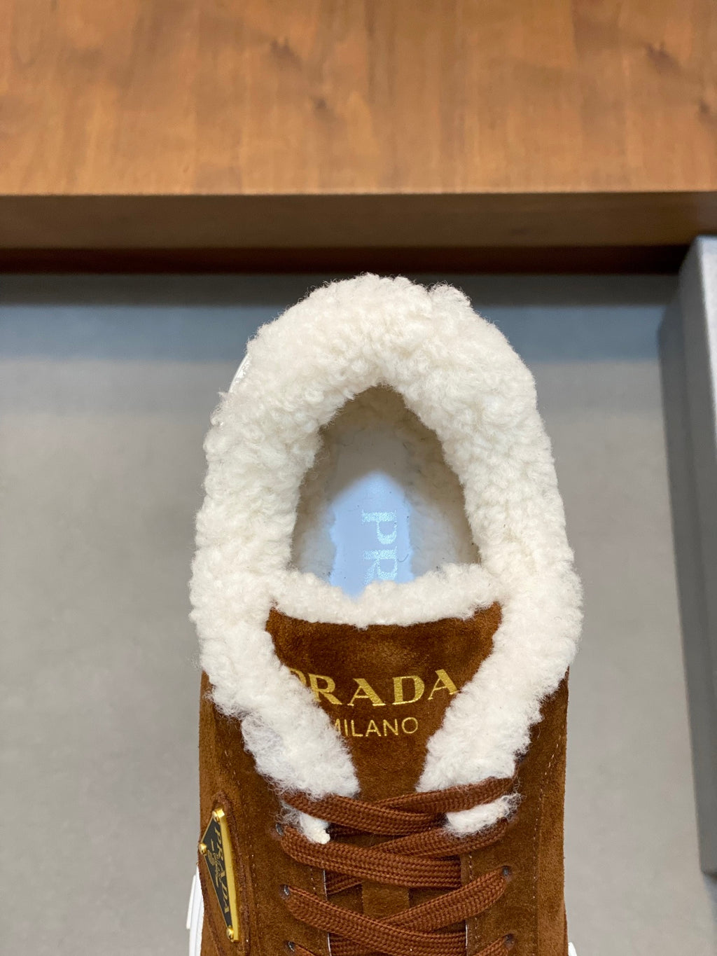 Brown suede lace-up sneaker with shearling collar and Prada branding on tongue