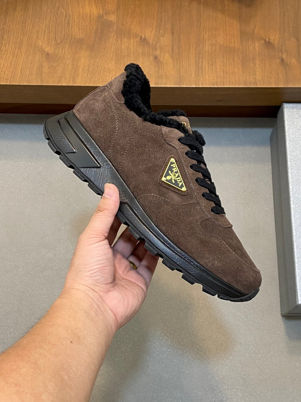 Brown suede Prada sneaker with black faux-fur collar, lace-up closure, chunky rubber sole