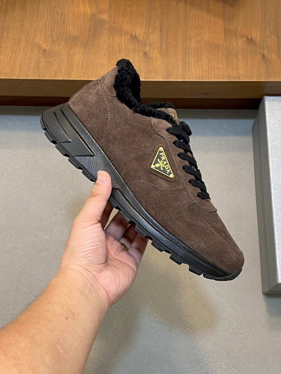 Brown suede Prada sneaker with black faux-fur collar, lace-up closure, chunky rubber sole