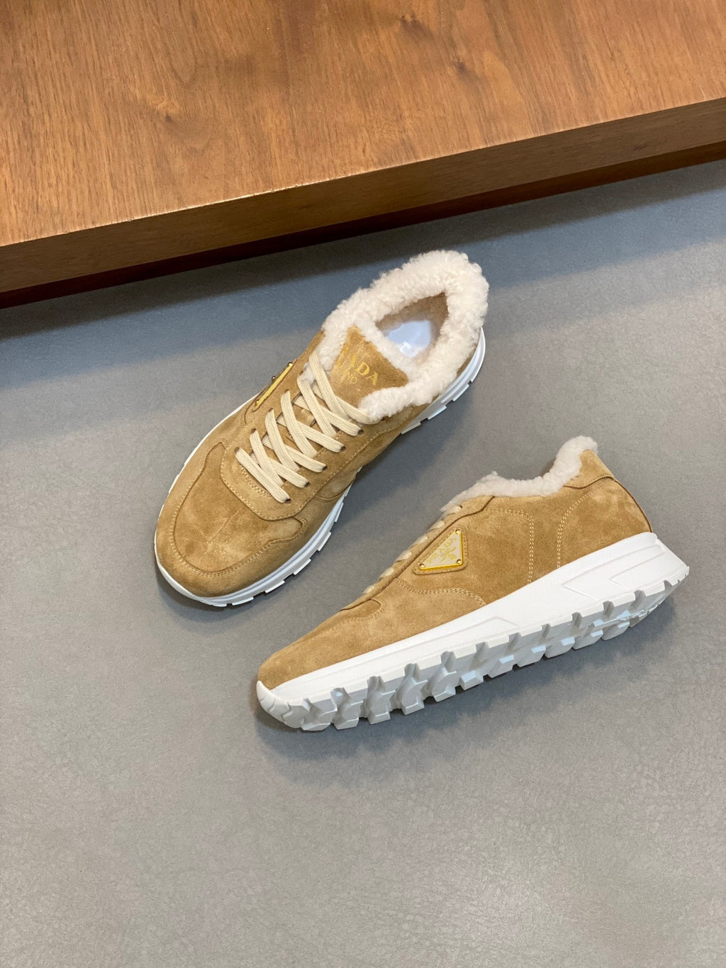 Prada unisex tan suede sneakers pair with white laces, shearling trim, and tread sole