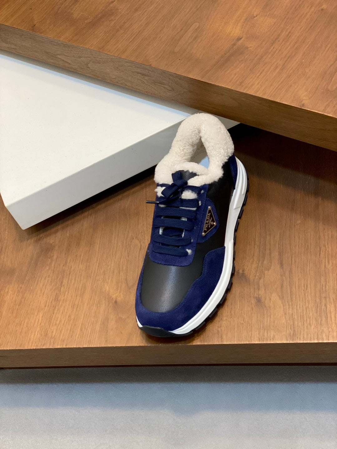 Single Prada unisex sneaker, dark blue upper with plush collar and white rubber sole.