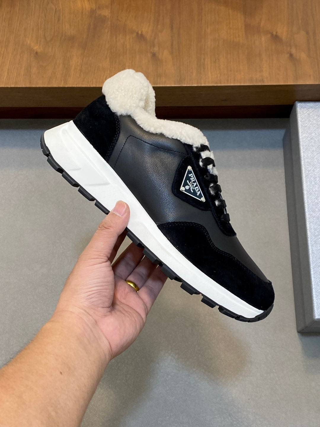 Prada unisex black lace-up sneaker held in hand, sherpa collar and white sole