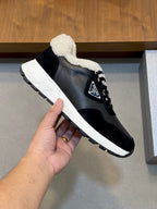 Black Prada lace-up sneaker held in hand, white sole and sherpa collar detail.