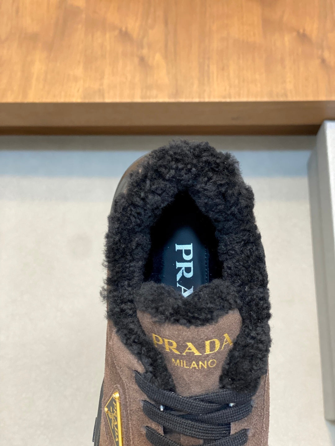 Prada sneaker interior view with blue PRADA label and brown suede exterior