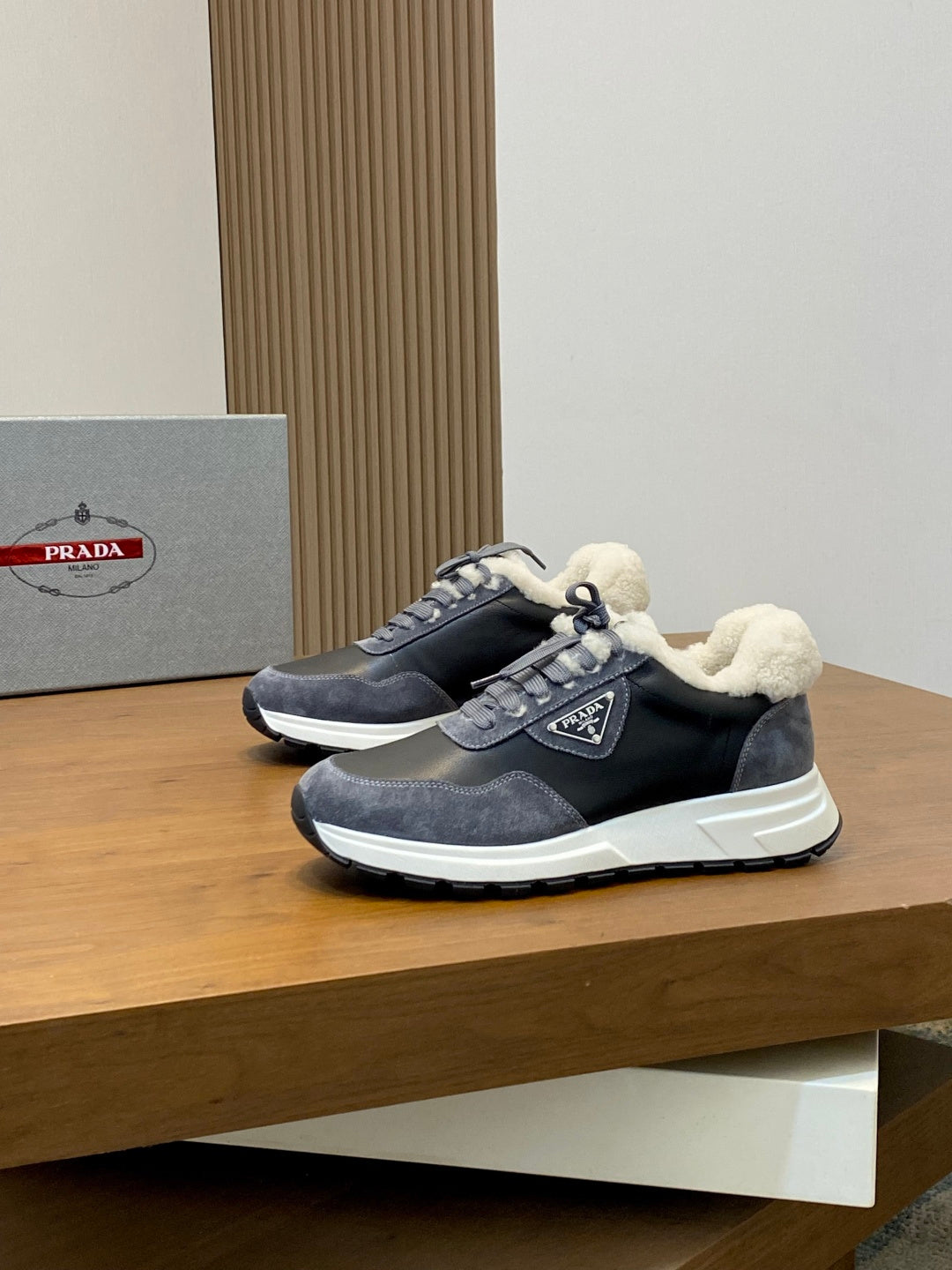 Prada unisex sneakers on display, dark uppers with fleece lining, lace-up style, white sole.
