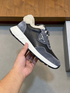 Prada unisex sneakers held in hand; dark gray upper with shearling collar and sole