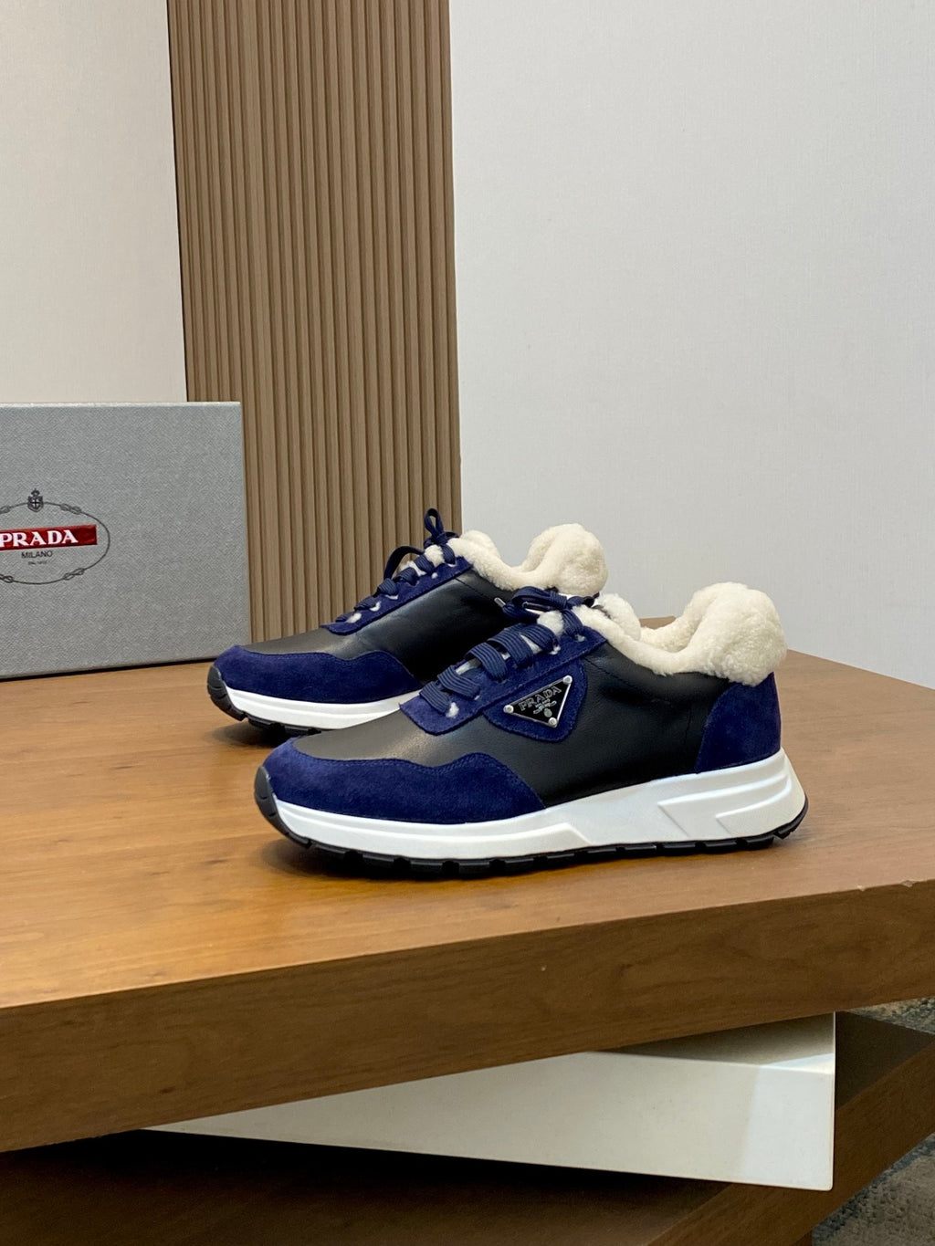 Prada unisex sneakers on display: dark blue with plush lining, white sole, lace-up closure.