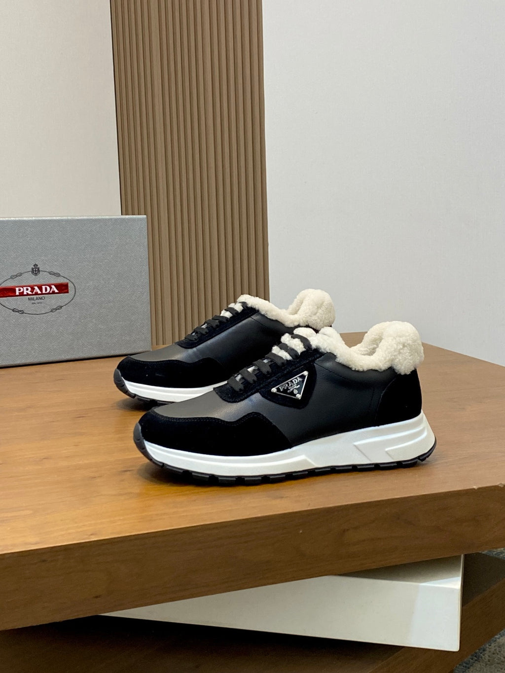 Prada unisex sneaker side view in black with sherpa collar, laces, and white sole
