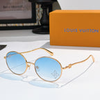 Round sunglasses with gold frame and light blue gradient lenses, rhinestone detail at lens