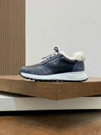 Prada unisex sneakers side view, dark navy/gray uppers with sherpa trim and white sole.