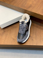 Prada unisex sneakers, single shoe on shelf, dark uppers with fleece collar and white midsole.
