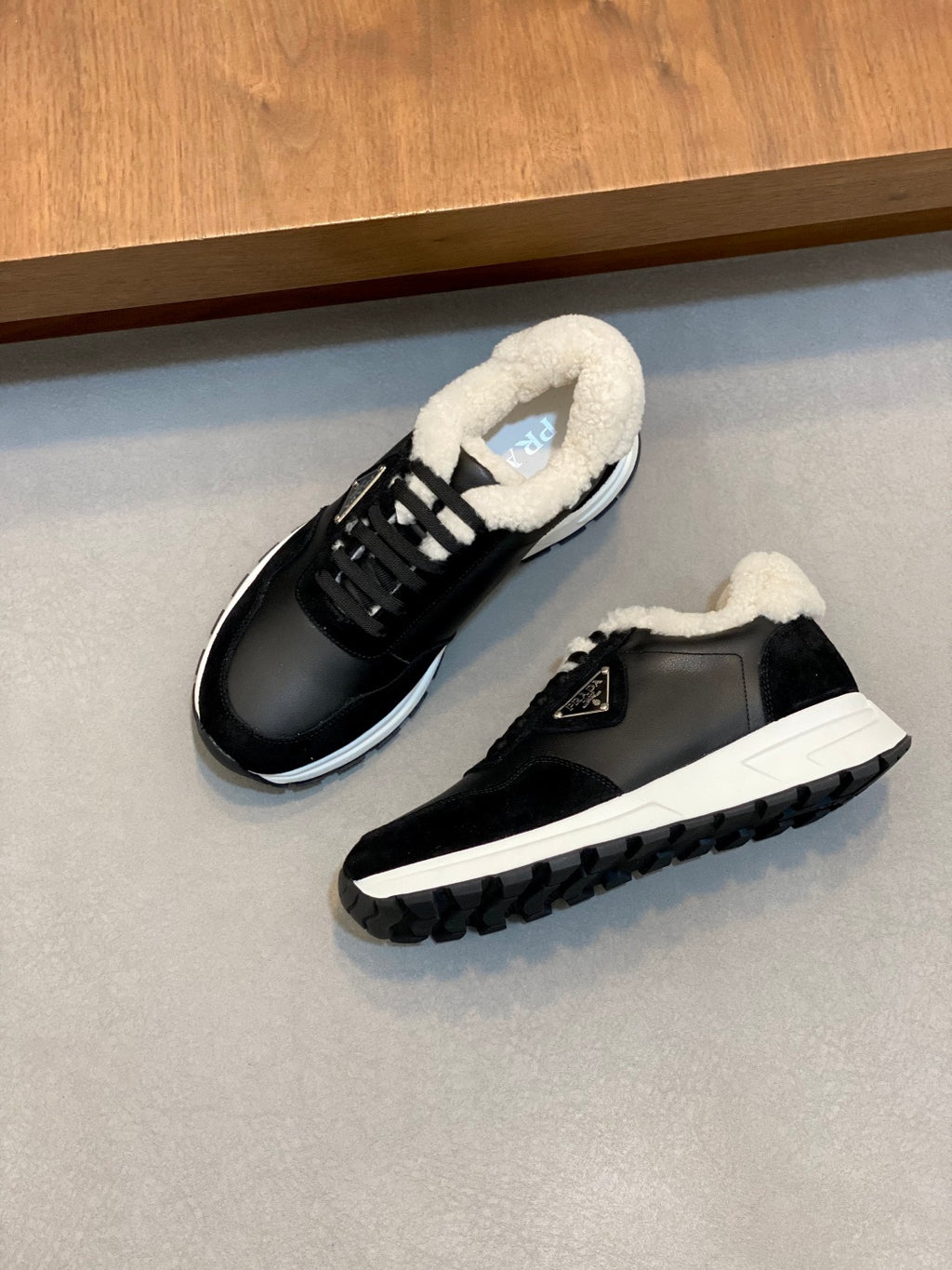 Black Prada sneakers with fluffy tongue lining, laces, and white outsole, overhead.
