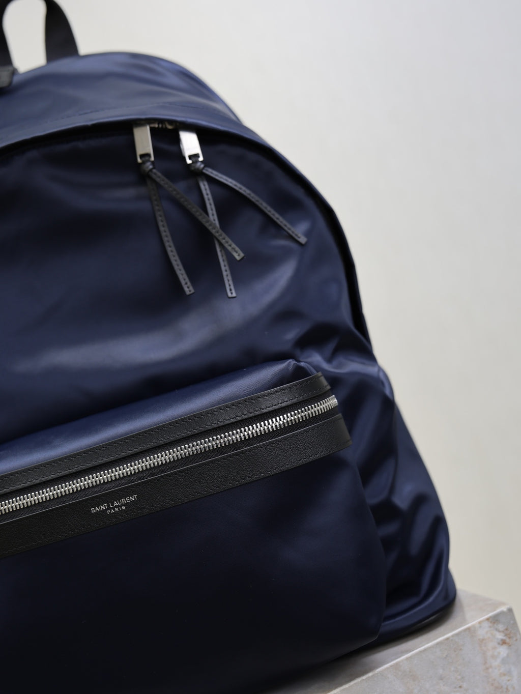 YSL navy backpack close-up of front zipper, drawcord ties, and logo label