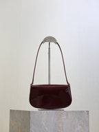 Mini shoulder bag in dark burgundy patent leather with curved flap and gold hardware