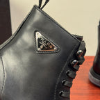 Black leather ankle boot close-up: Prada logo patch and lace-up front panel.