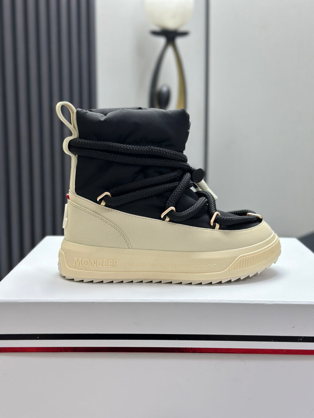 Moncler single high-top sneaker on display, black upper with cream sole and laces