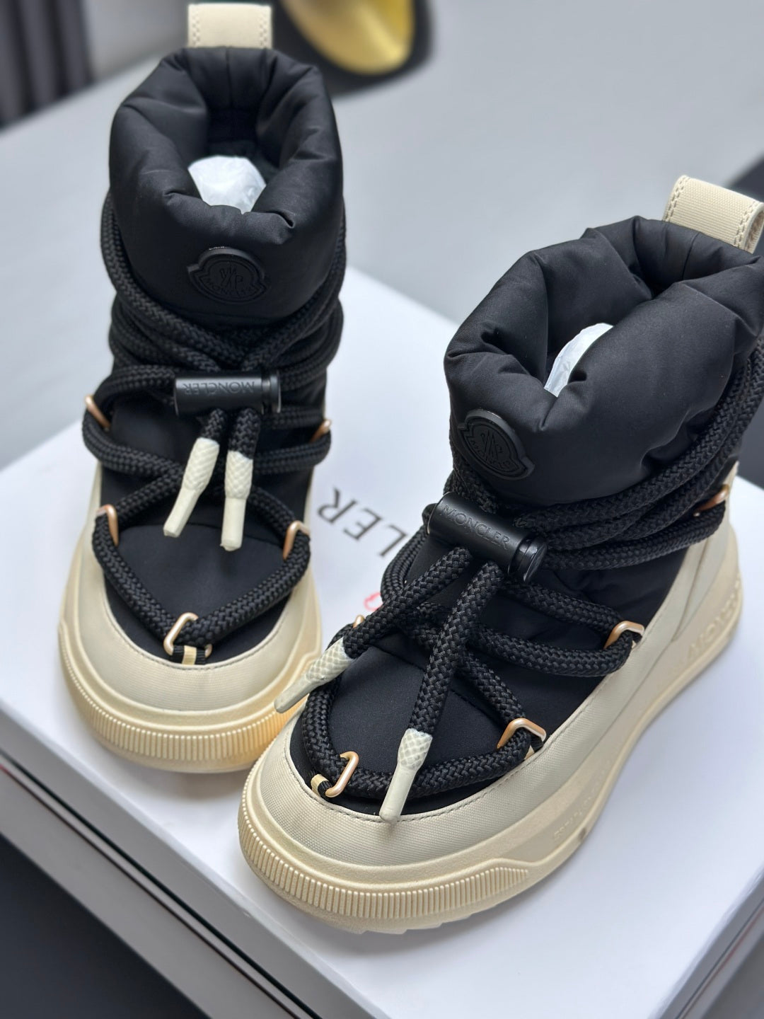 Moncler high-top sneakers with black padded collars, cream soles, and lace-up ties