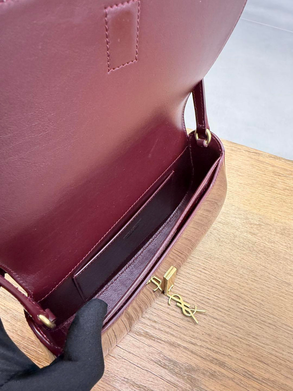 YSL burgundy mini bag open with gold YSL logo hardware and visible interior