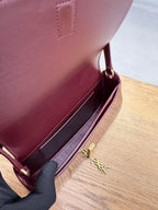 YSL burgundy mini bag open with gold YSL logo hardware and visible interior