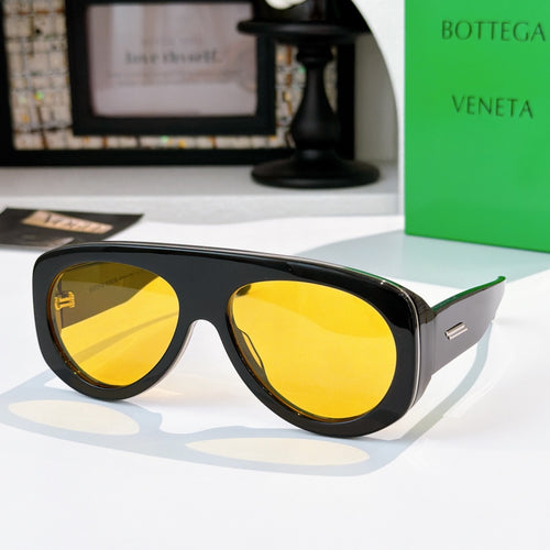 Black oversized sunglasses with yellow mirrored lenses and green-accent temples.