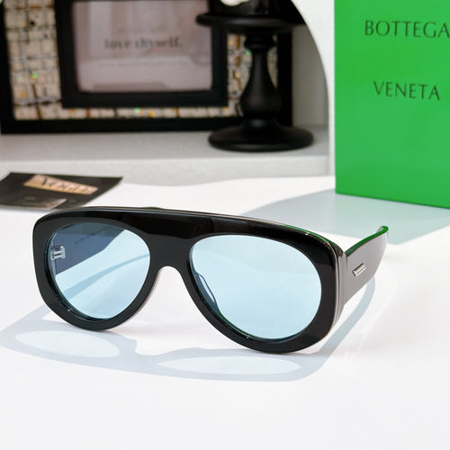 Black oversized sunglasses with blue mirrored lenses and green-accent temples.