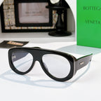 Black oversized sunglasses with clear-to-light lenses and green-accent temples.