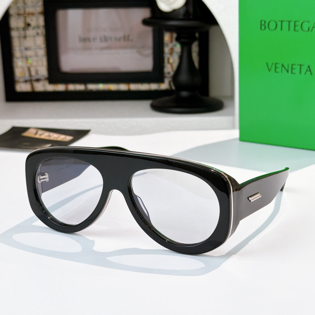 Black oversized sunglasses with clear-to-light lenses and green-accent temples.