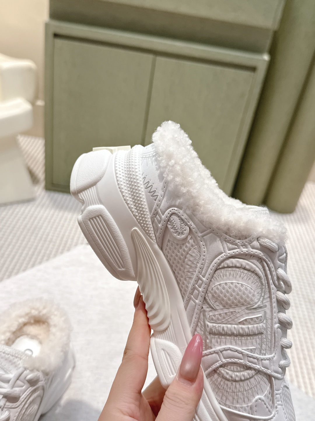 White sneaker with fur collar and thick tread sole, shown from the heel side