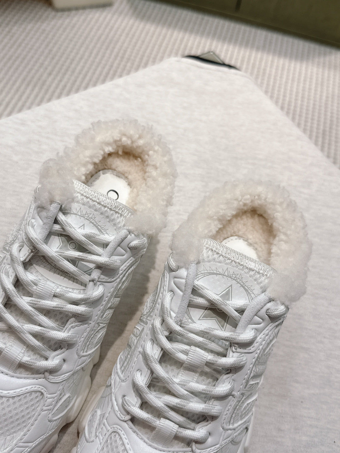 Close-up of white lace-up sneakers with fuzzy lining and textured overlay detailing