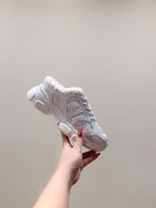 White sneaker held up showing lace-up upper, fuzzy collar, and cushioned outsole
