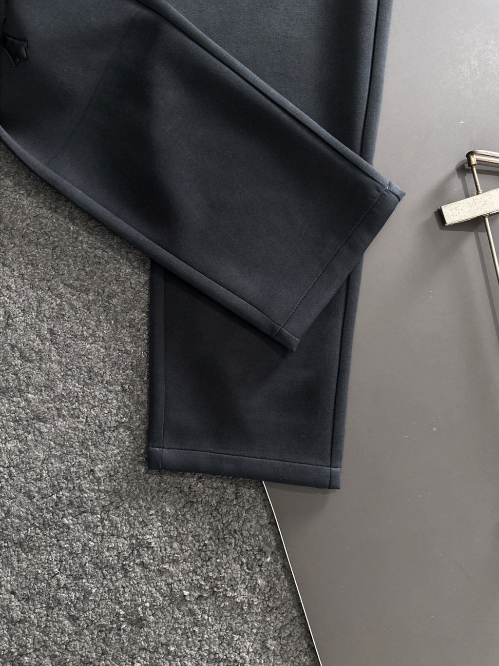Dark pants leg with straight cut and neatly finished hem