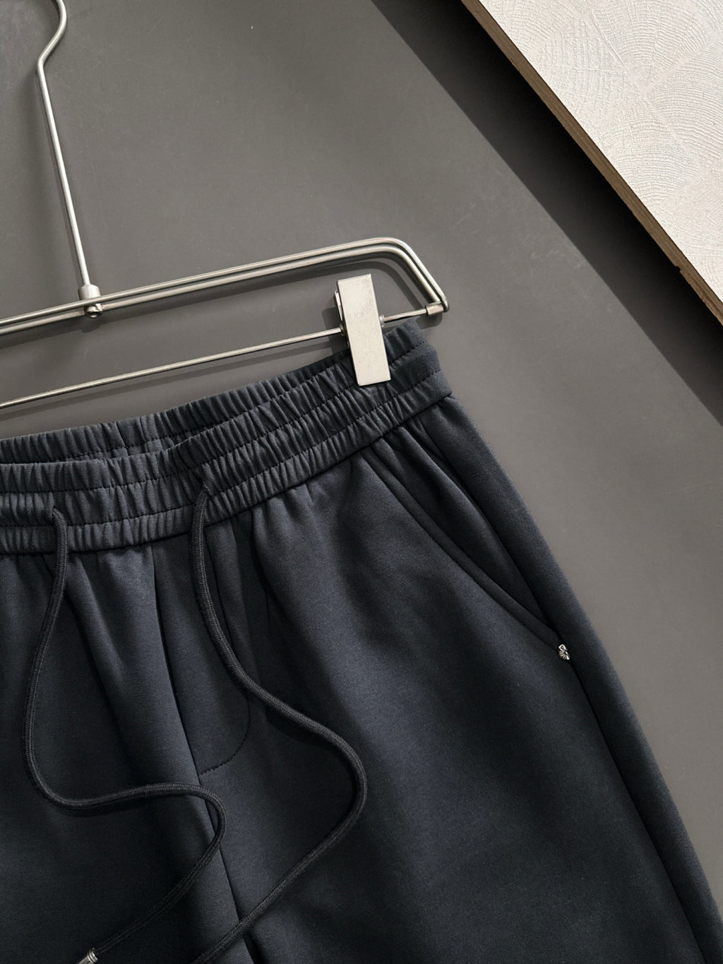 Dark pants waistband close-up with elastic gathers and drawstring cord