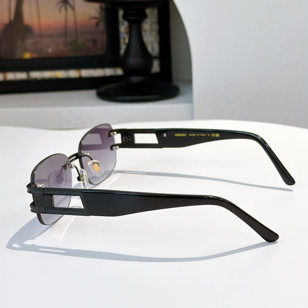 Sunglasses with purple lenses and black frame, gold-tone hardware on temples
