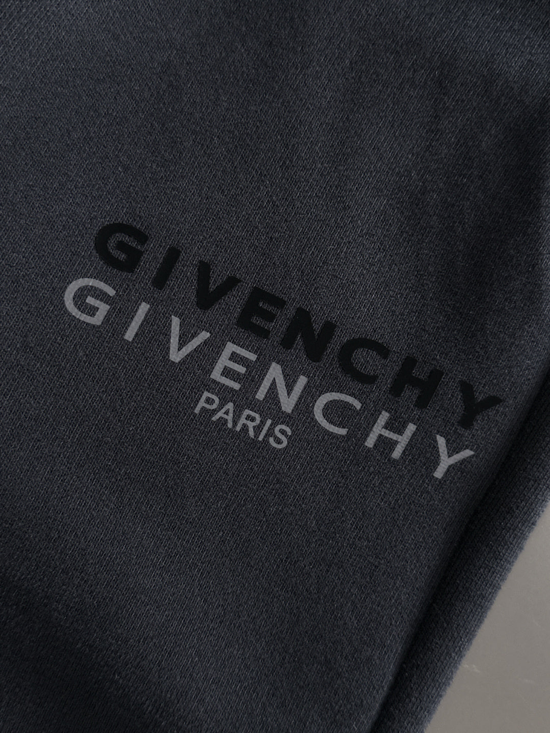 Close-up of black sweatpants with GIVENCHY PARIS text logo print