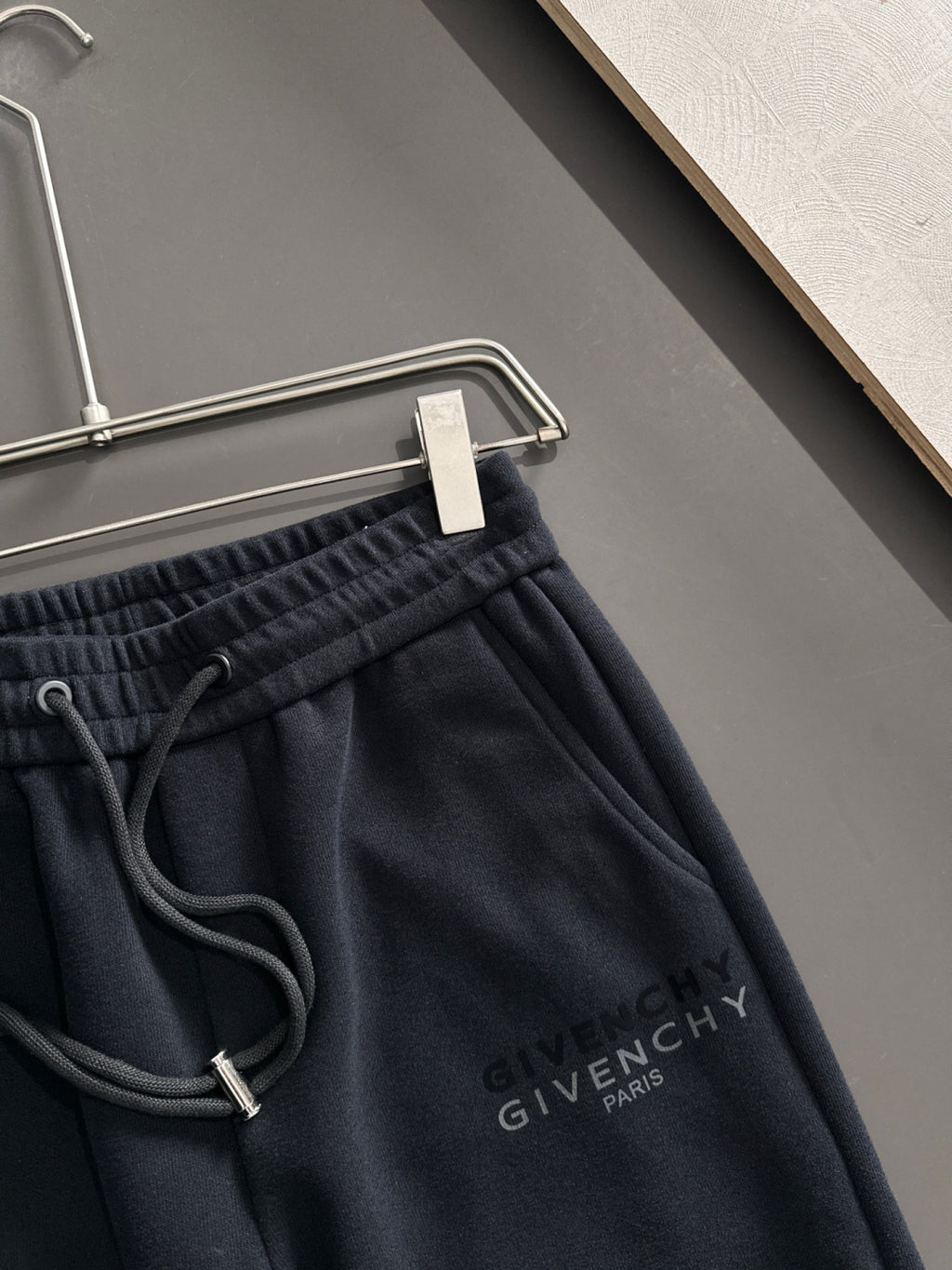 Close-up of black elastic-waist drawstring sweatpants with Givenchy Paris logo on chest