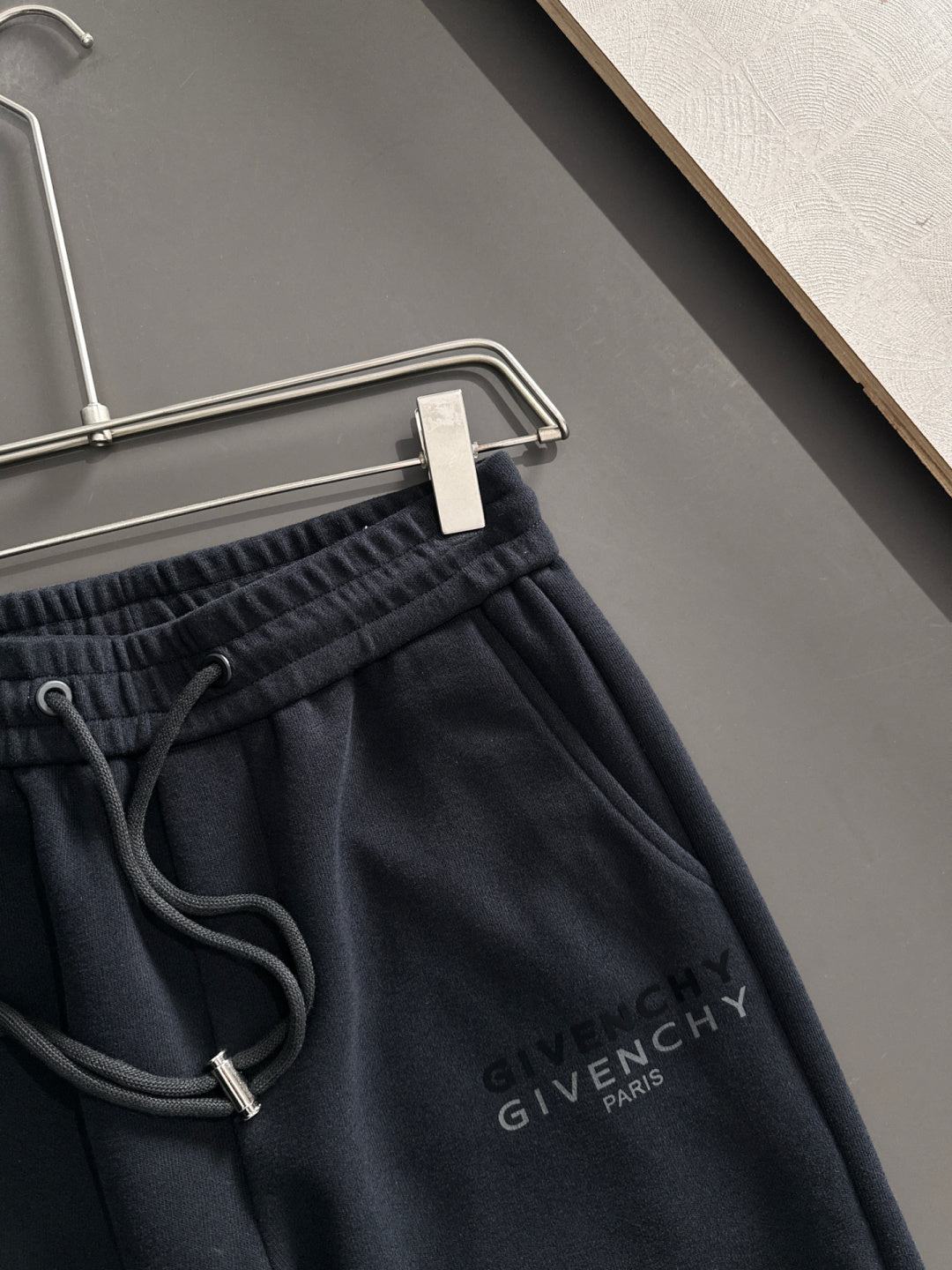 Close-up of black elastic-waist drawstring sweatpants with Givenchy Paris logo on chest