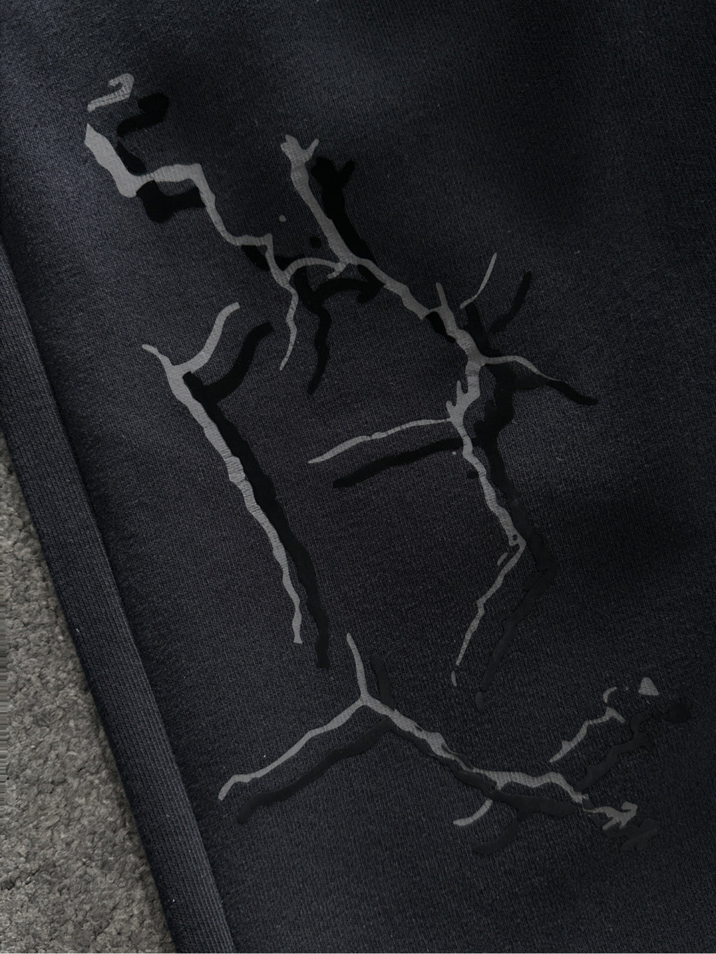 Close-up of black sweatpants fabric with abstract crack-style graphic print
