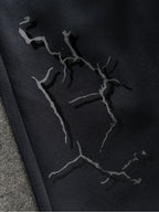 Close-up of black sweatpants fabric with abstract crack-style graphic print