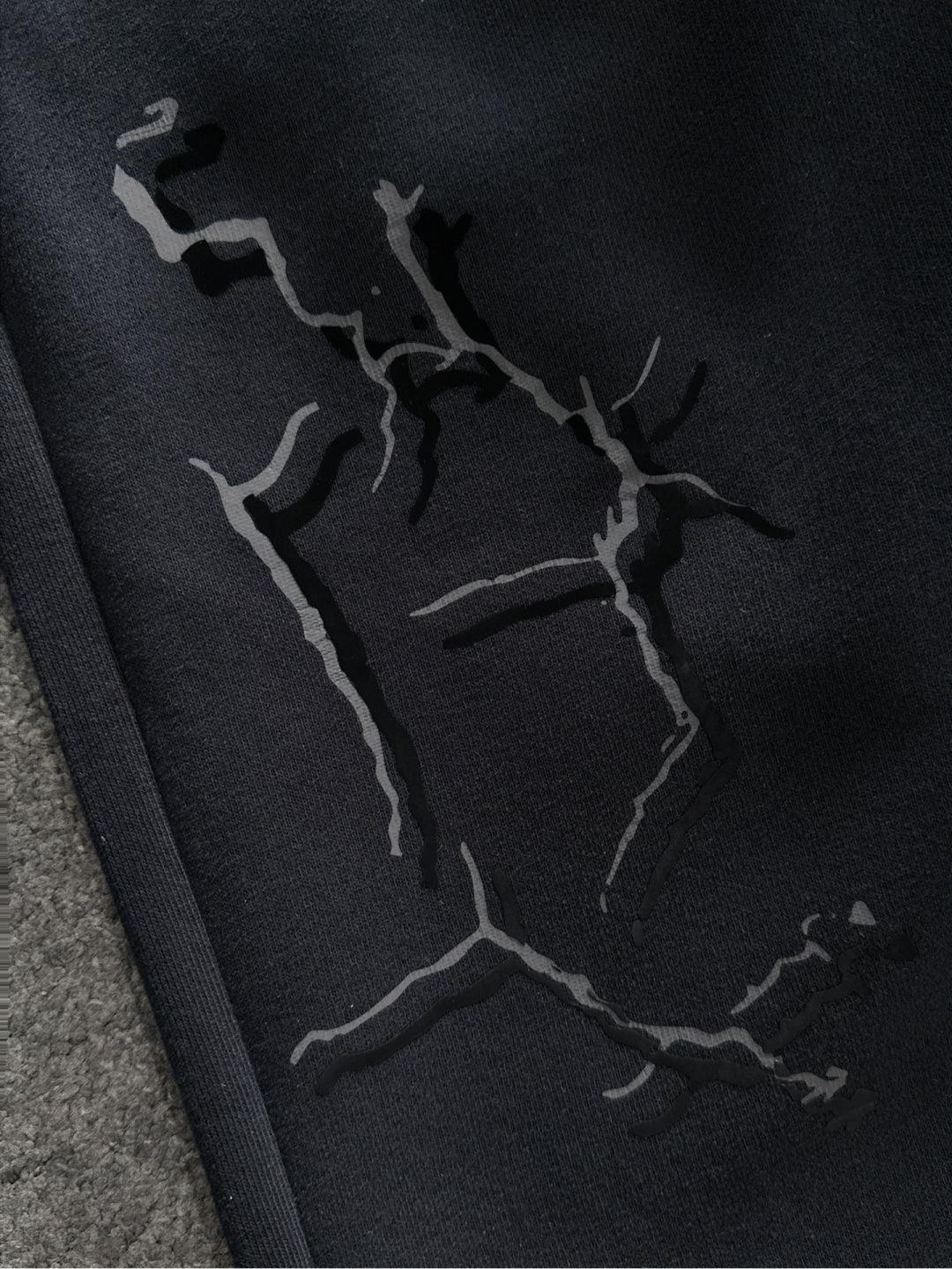Close-up of black sweatpants fabric with abstract crack-style graphic print