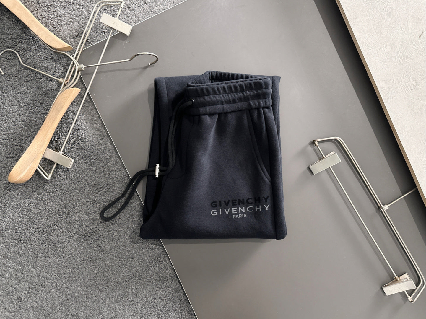 Black Givenchy Paris drawstring pants with elastic waistband, displayed folded on hangers