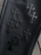 Dark pants with stitched cross embroidery on the front
