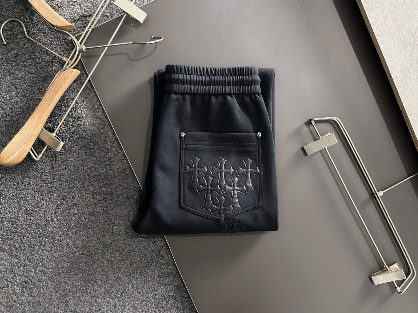 Dark pants with elastic waist and drawstring, side pocket with stitched cross design