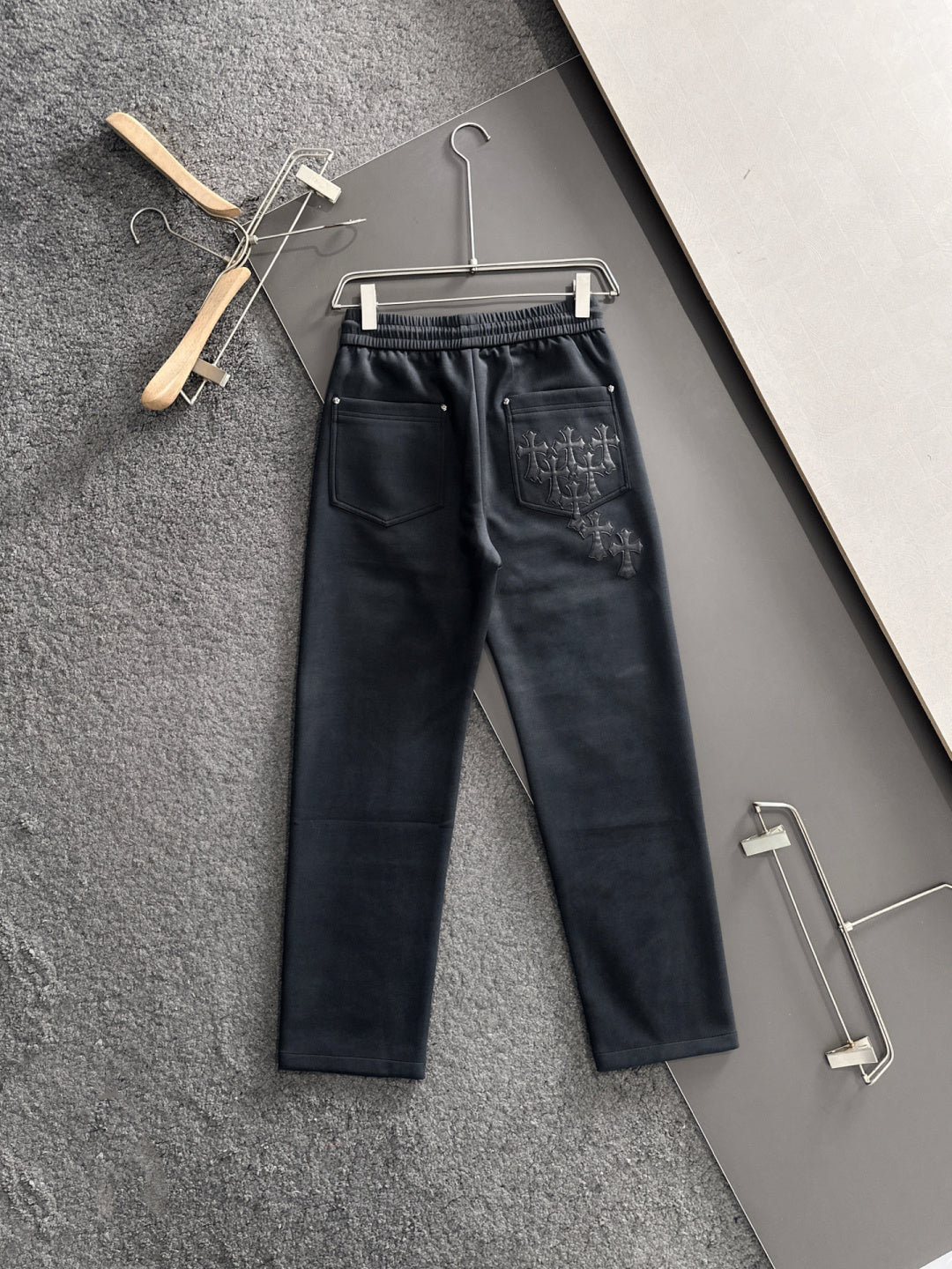 Dark pants with elastic waistband and drawstring, side pockets and cross embroidery